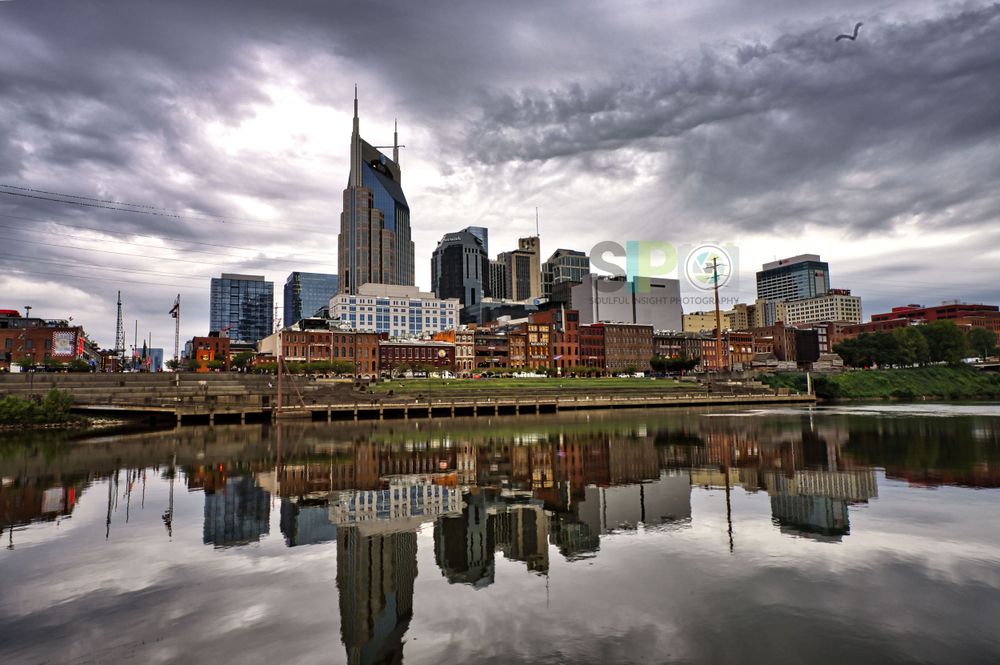 Nashville skyline reflecting in the Cumberland River under dramatic stormy clouds.