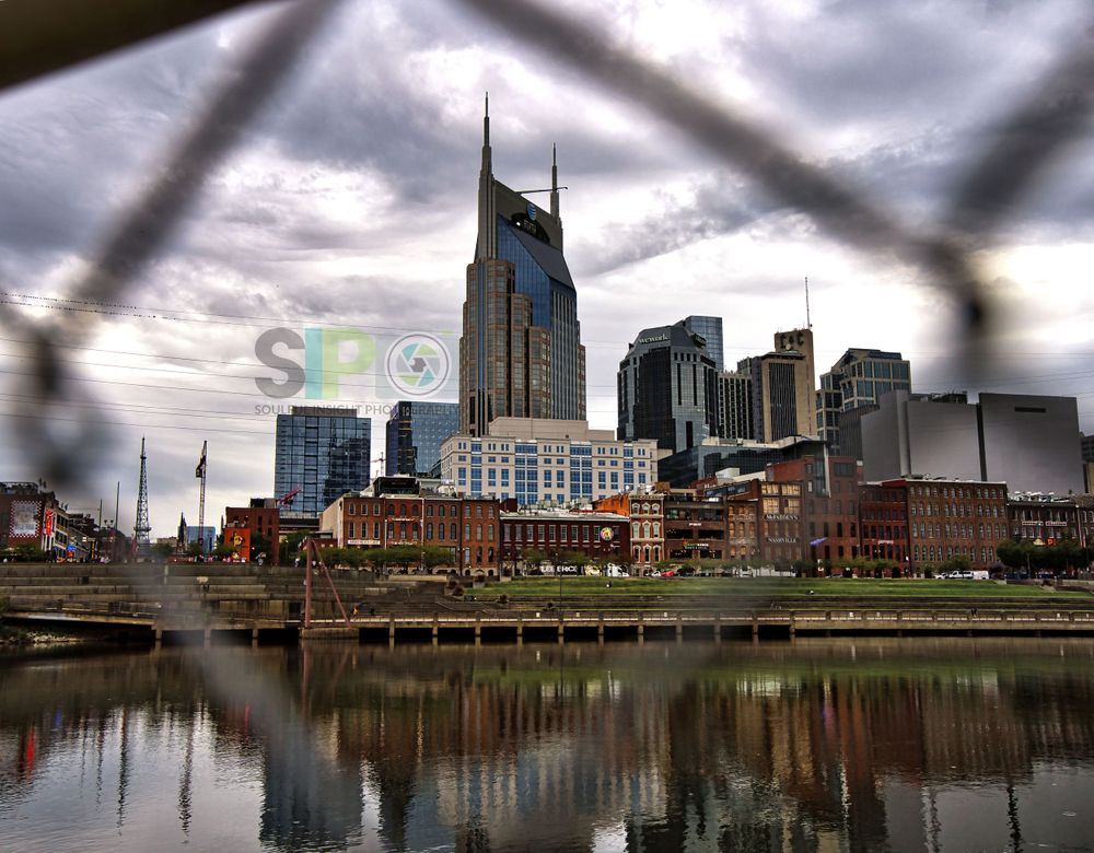 Nashville's downtown skyline mirrored in calm waters with moody storm clouds overhead.