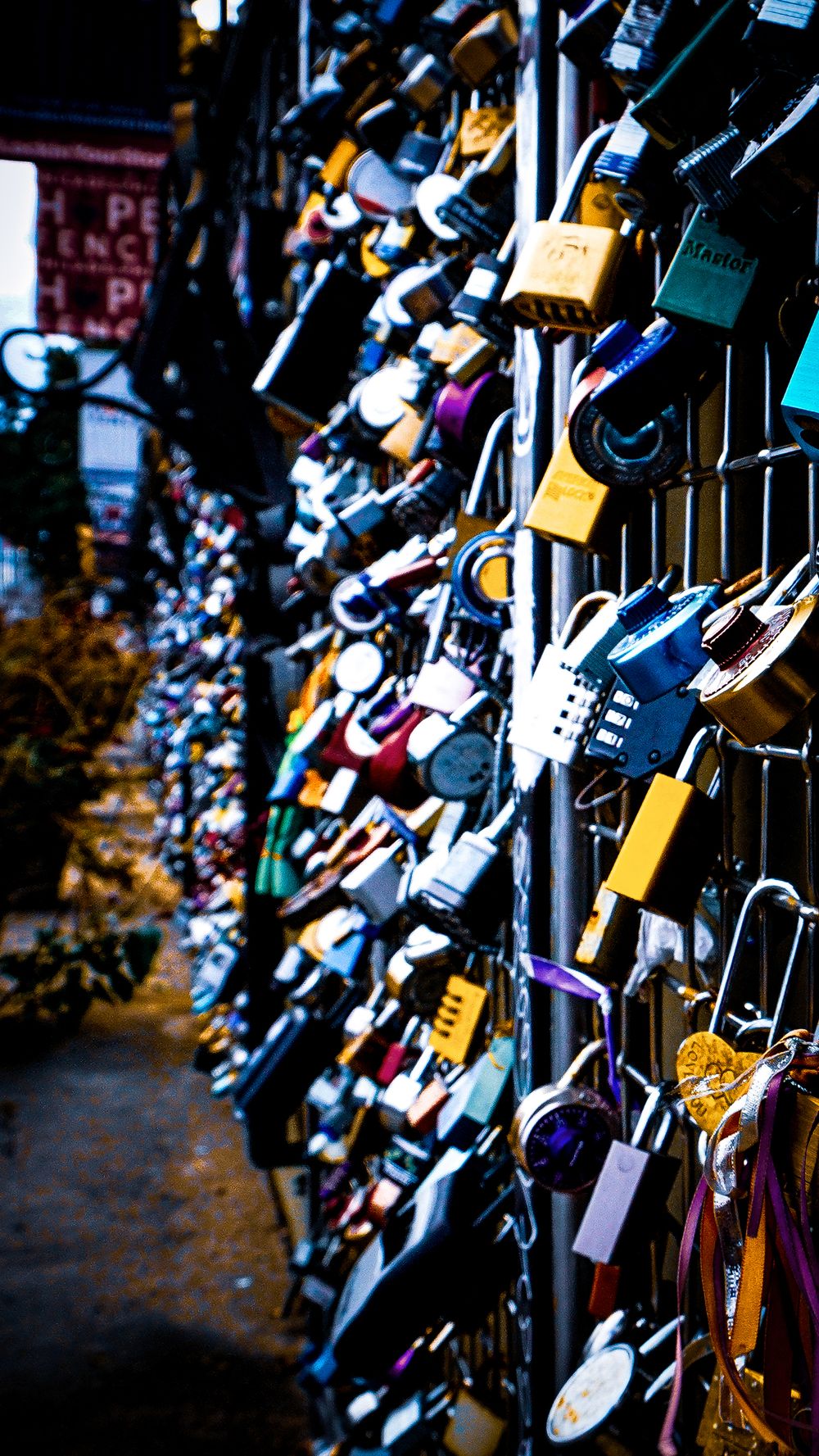 Colorful love locks attached to a fence creating a dense pattern of padlocks in various sizes and colors.