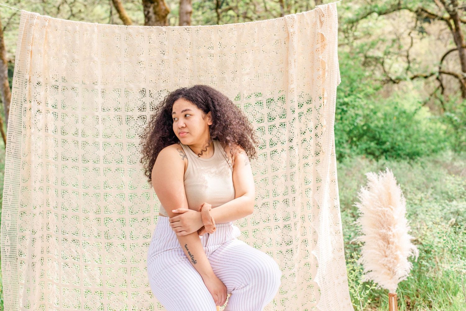 Outdoor portrait session with lace backdrop and wooden stool in a natural forest setting.