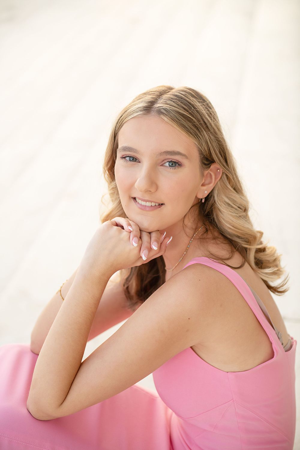 Soft portrait against white background in pink outfit.