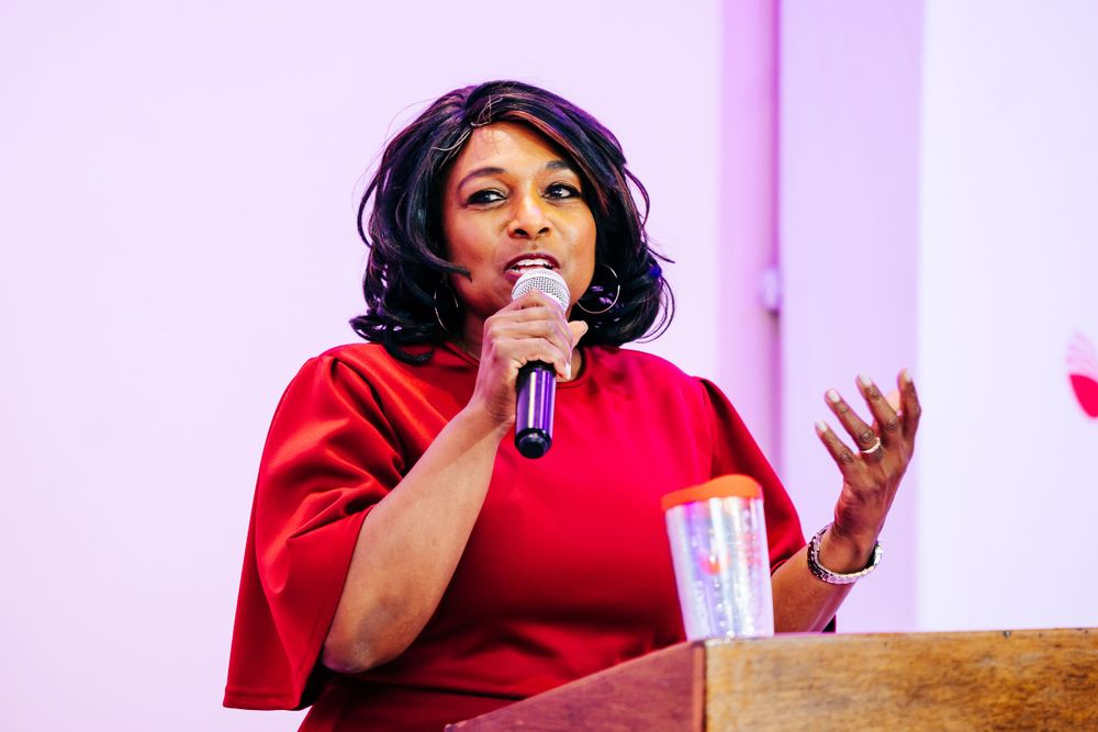 Presenter in red speaking at podium during Women's Red Apple Foundation program.
