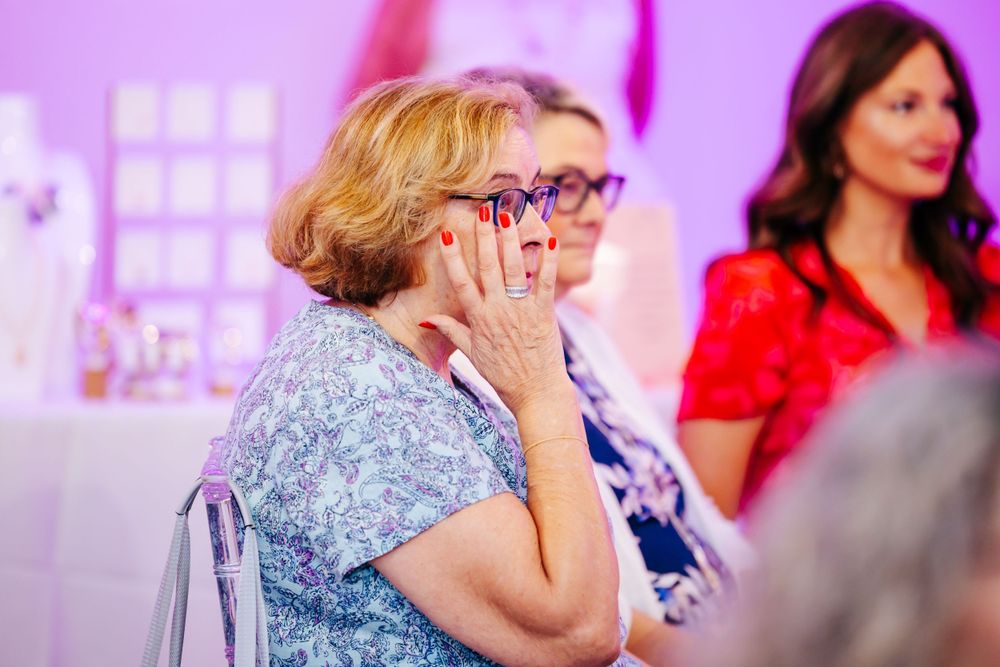 Group of attendees watching presentations at a pink-lit event with smiles and emotions on display.