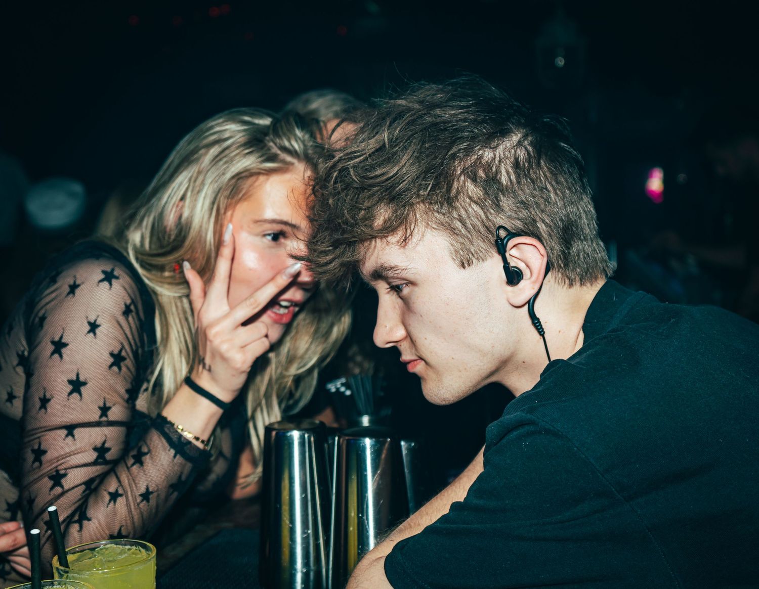 Blonde girl leaning in to let the bartender hear her order.