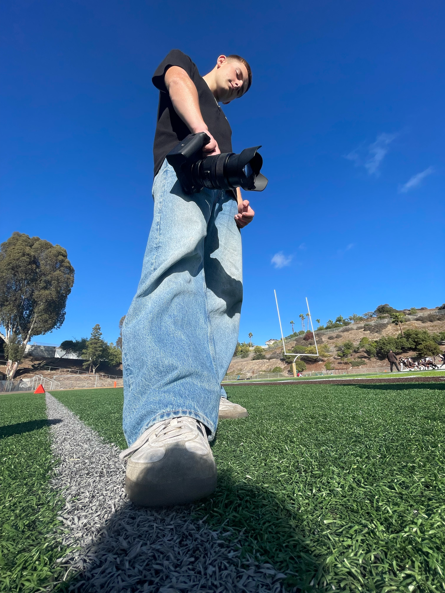 Low-angle shots of walking feet on grass showing movement sequence in blue jeans and sneakers.