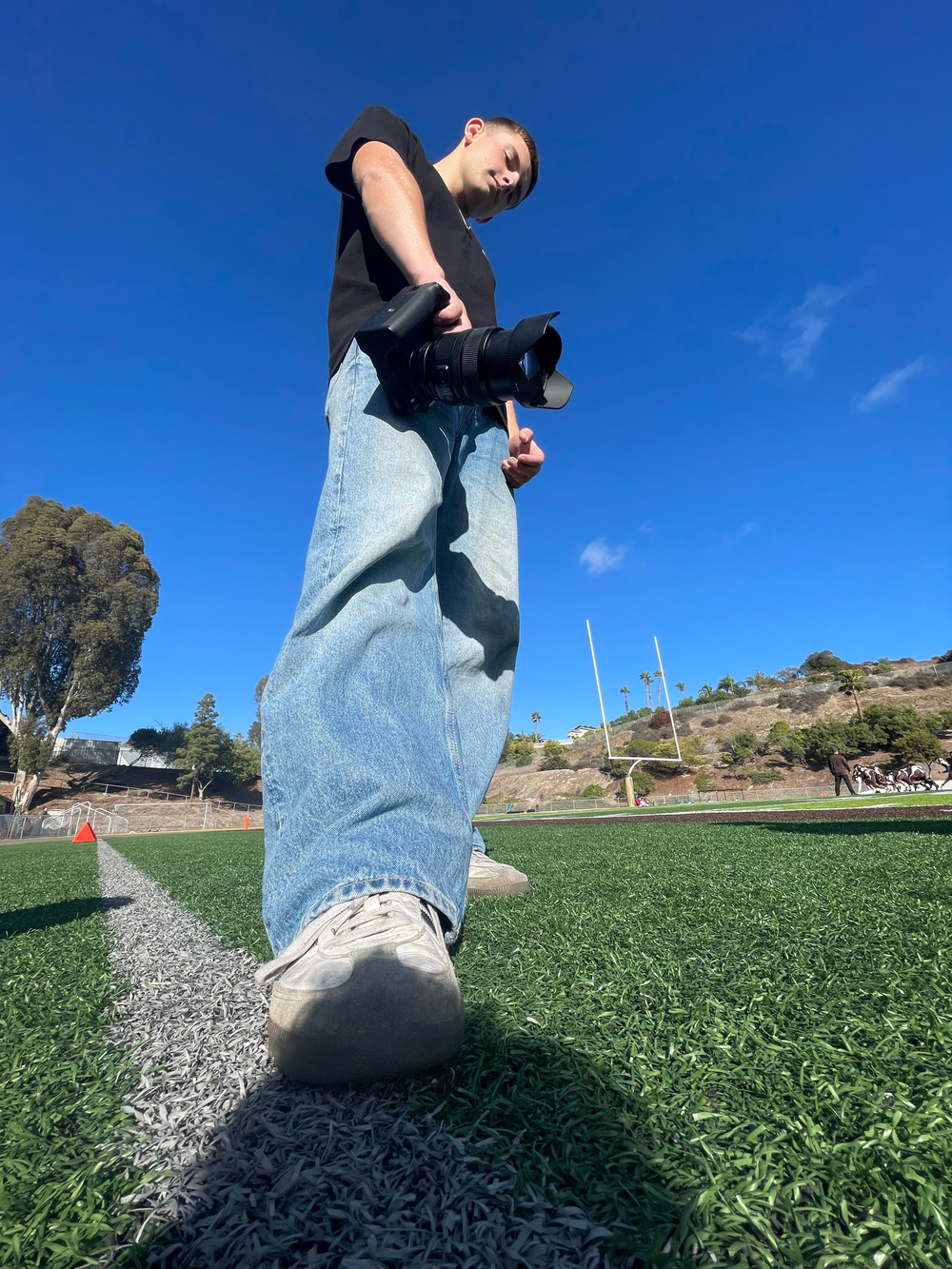 Low-angle shots of walking feet on grass showing movement sequence in blue jeans and sneakers.