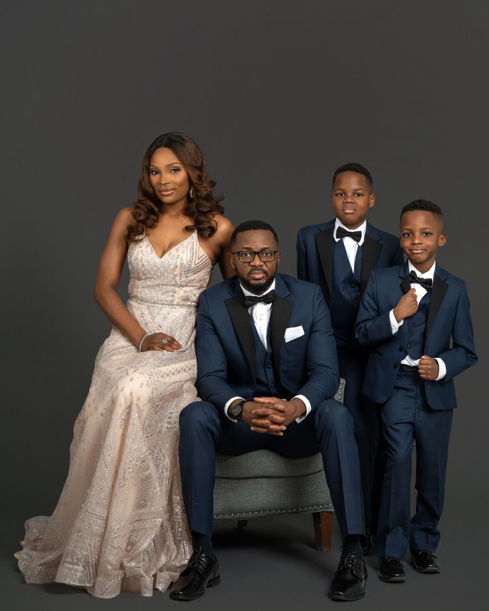 Formal family portrait with elegant attire against dark background.
