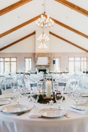 Elegant wedding reception venue with vaulted ceiling, crystal chandeliers, and round tables set with fine dinnerware.
