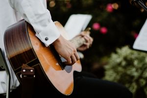 Close-up of musician's hands playing acoustic guitar during outdoor performance.