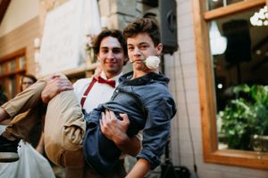Two wedding guests share a playful moment at an indoor venue.