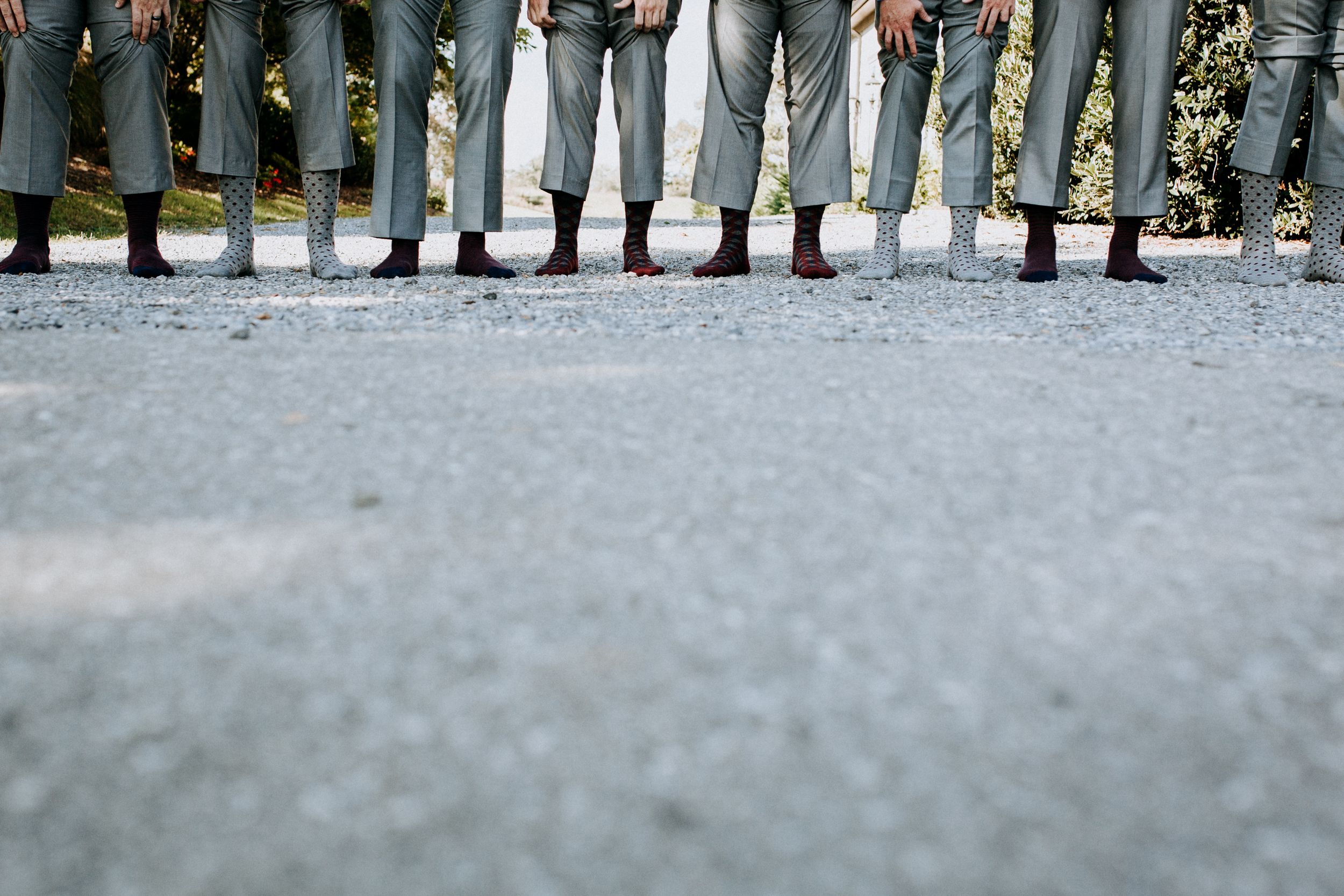 Creative photo of groomsmen's legs showing matching grey pants and colorful socks.