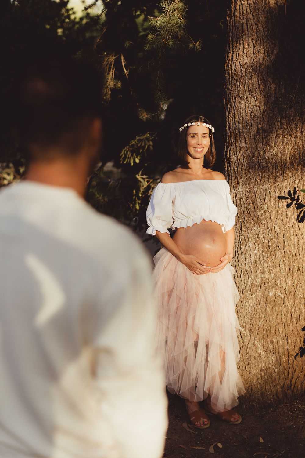 An intimate maternity session at sunset showing a couple in coordinated white and pink attire.