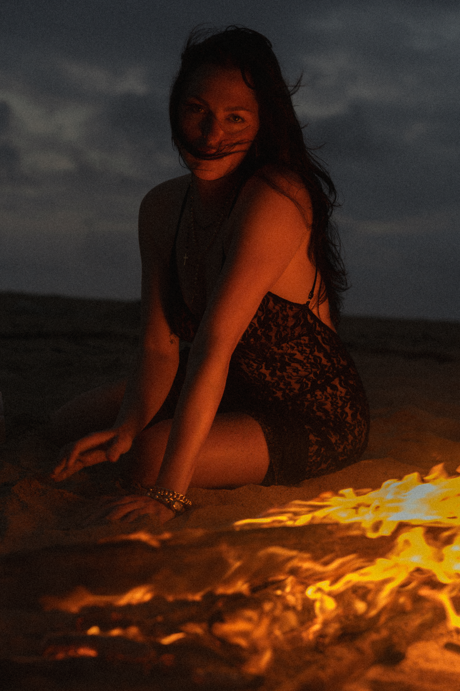 fire mixed with boiudor shoot, women is sitting on the sand surrounded by a ring of fire