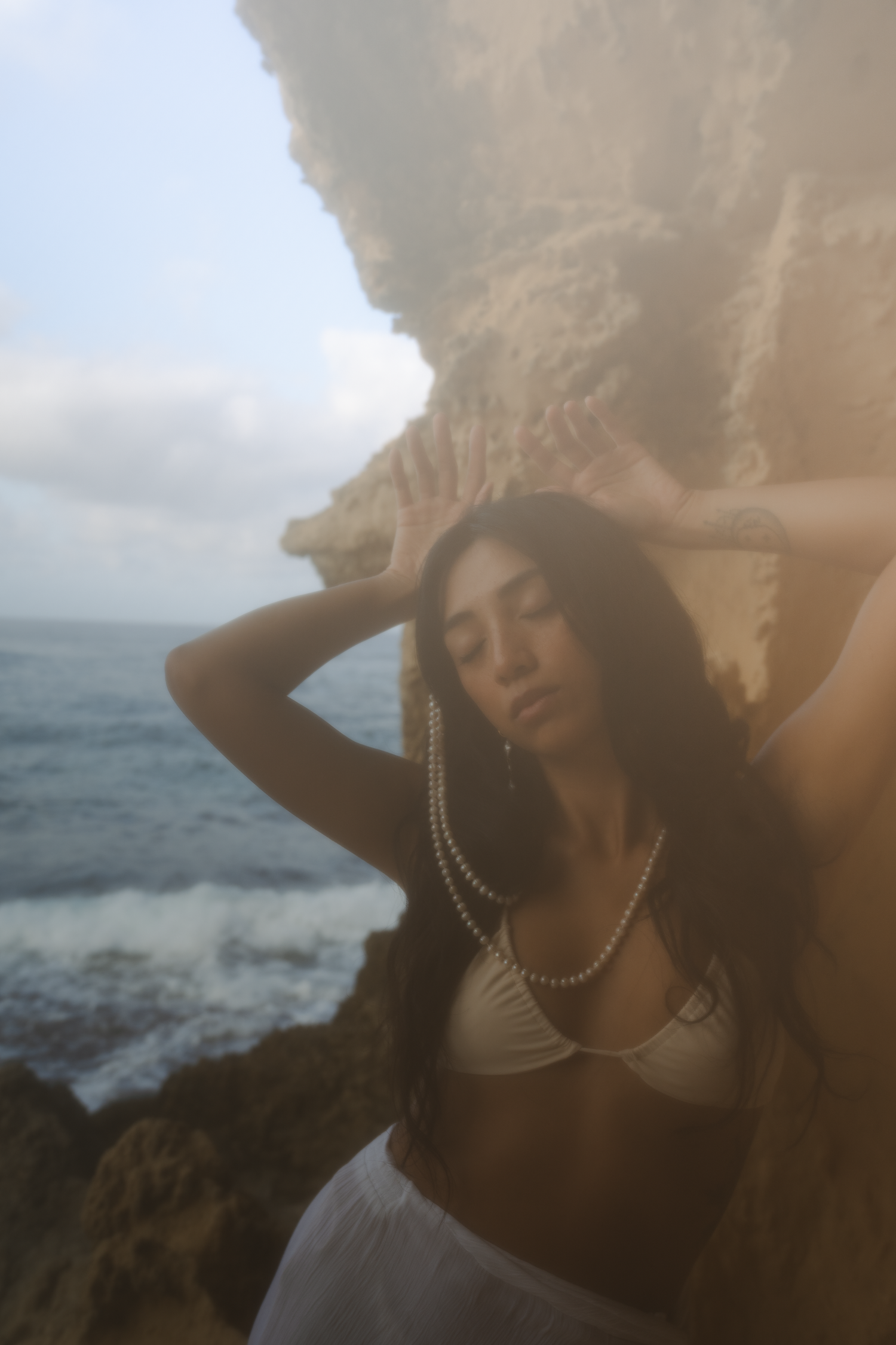 model in standing in a gave with light blue lighting in pearls
