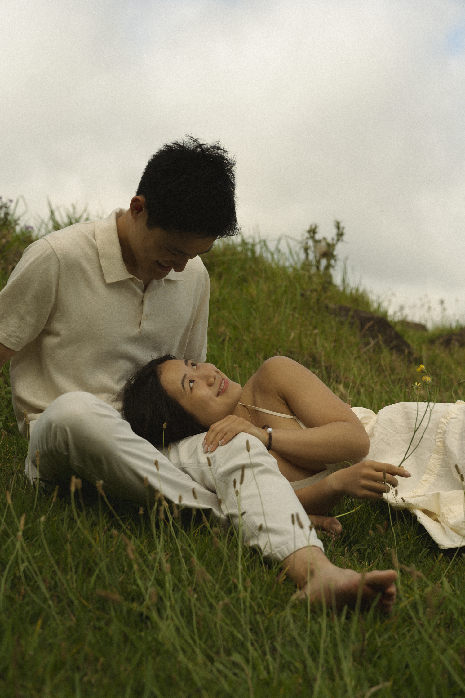 Couple laying in tall grass during a romantic outdoor photoshoot.