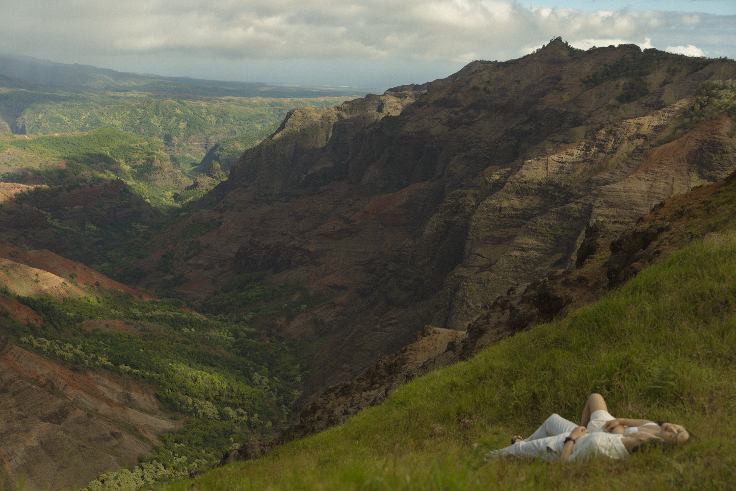couple laying in the grass at koke'e gazing at the clouds