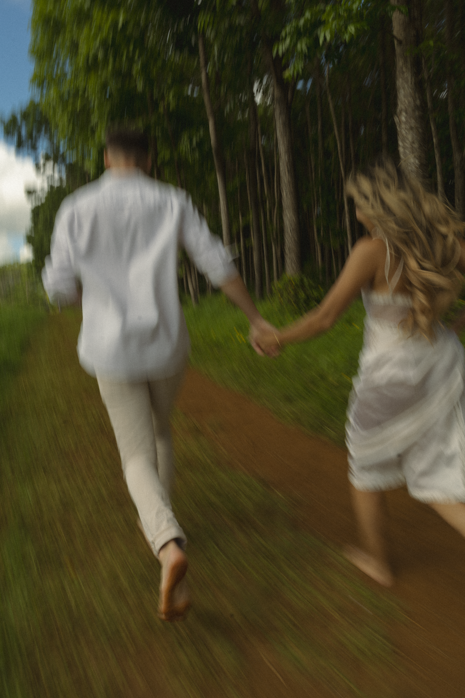 Movement sequence of two people in white walking through a sun-dappled forest path.