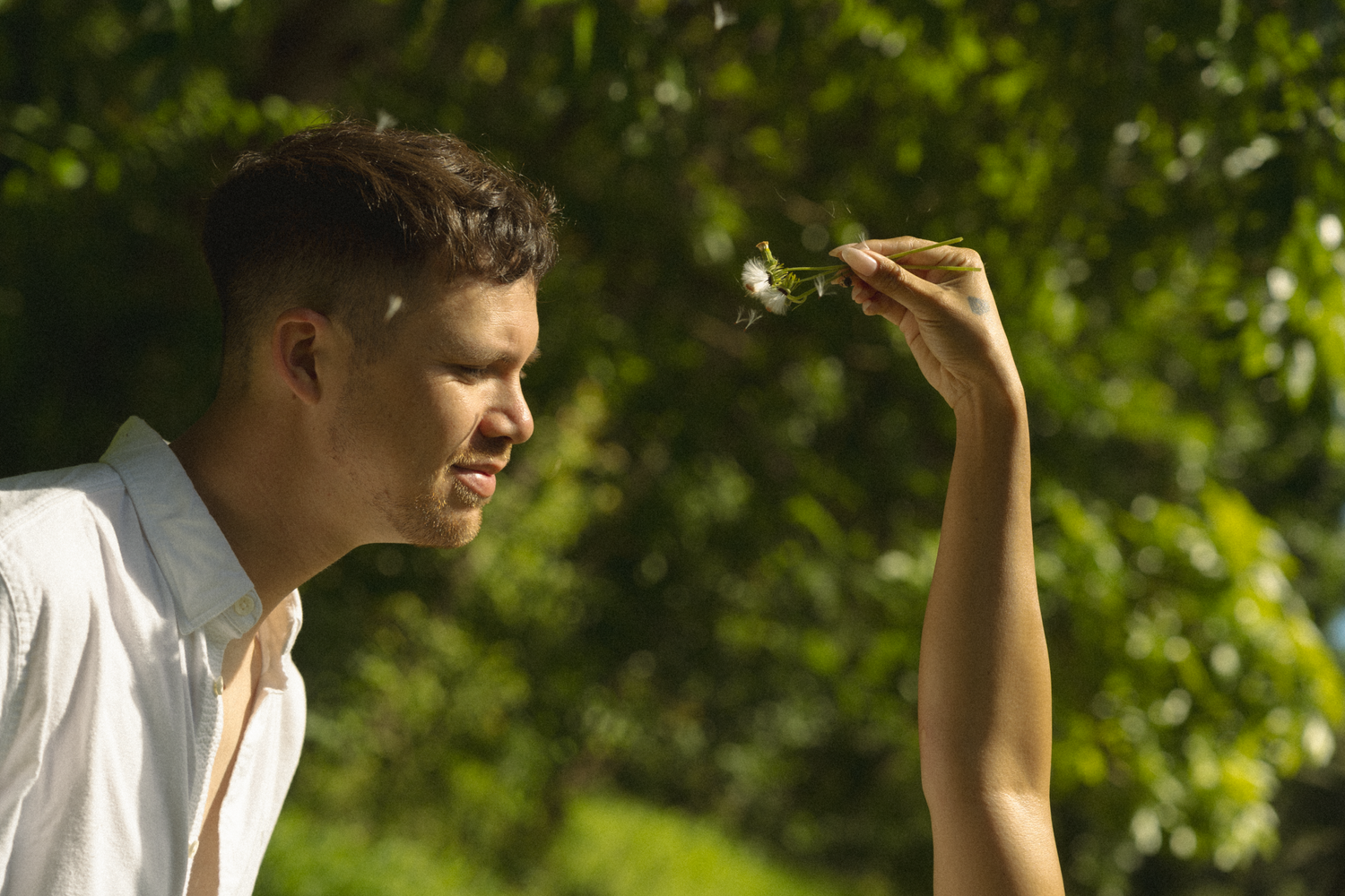 Two people dancing together outdoors with trees in the background.