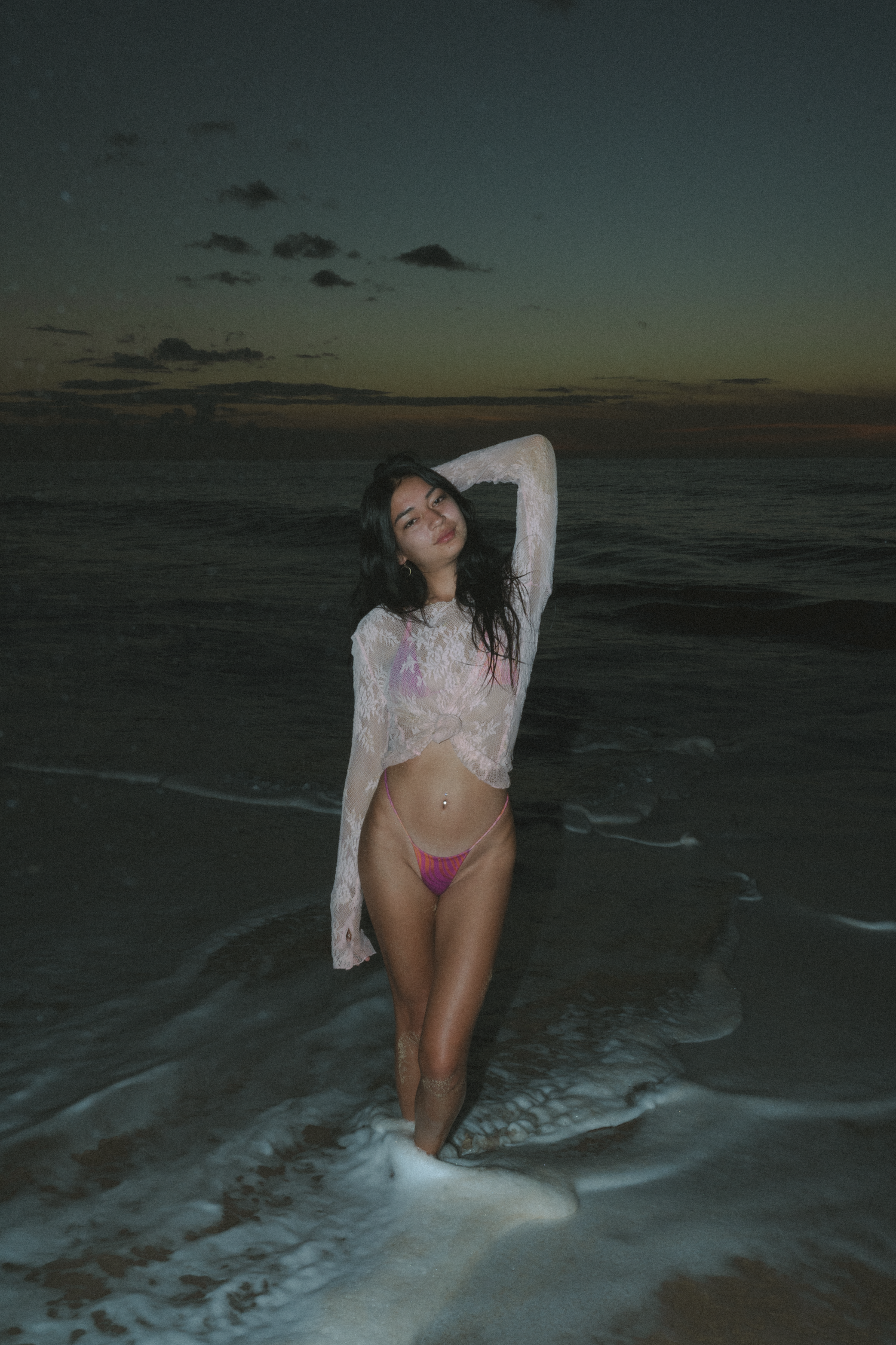 Beach photoshoot at dusk with ocean waves rolling onto shore.