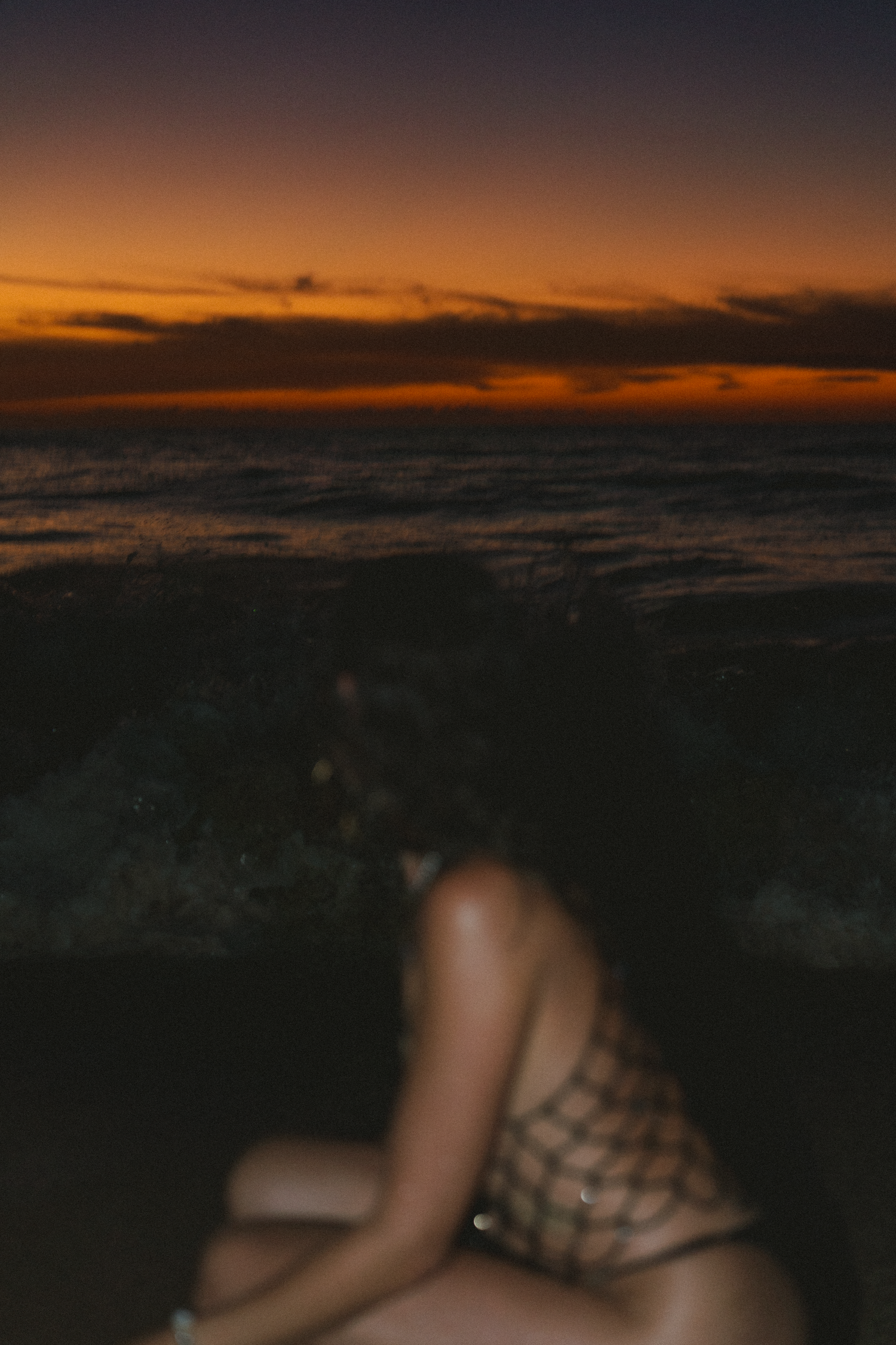 Dramatic orange and purple sunset sky over dark ocean horizon at dusk.