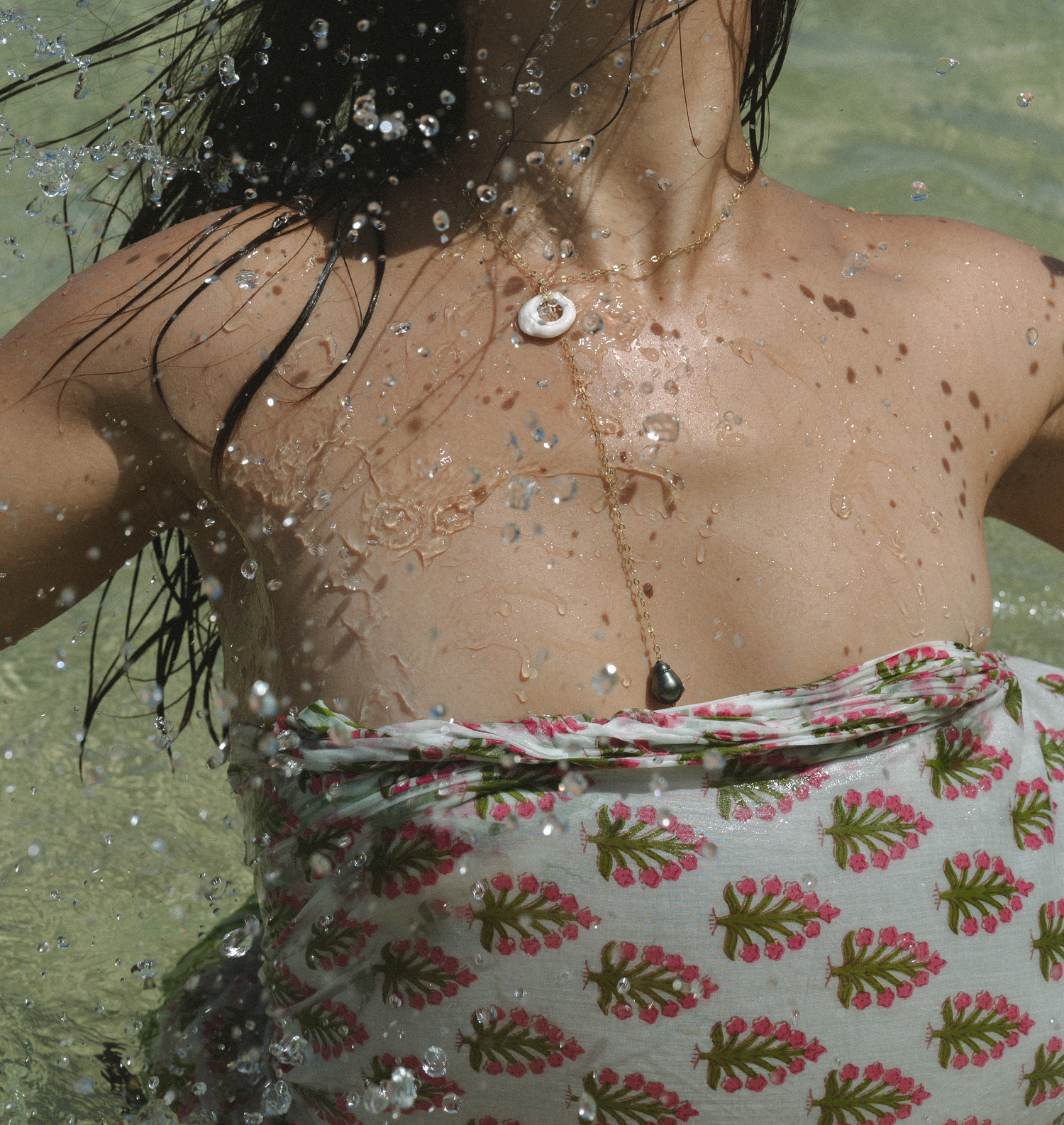 Water droplets on skin with floral patterned swimwear visible.