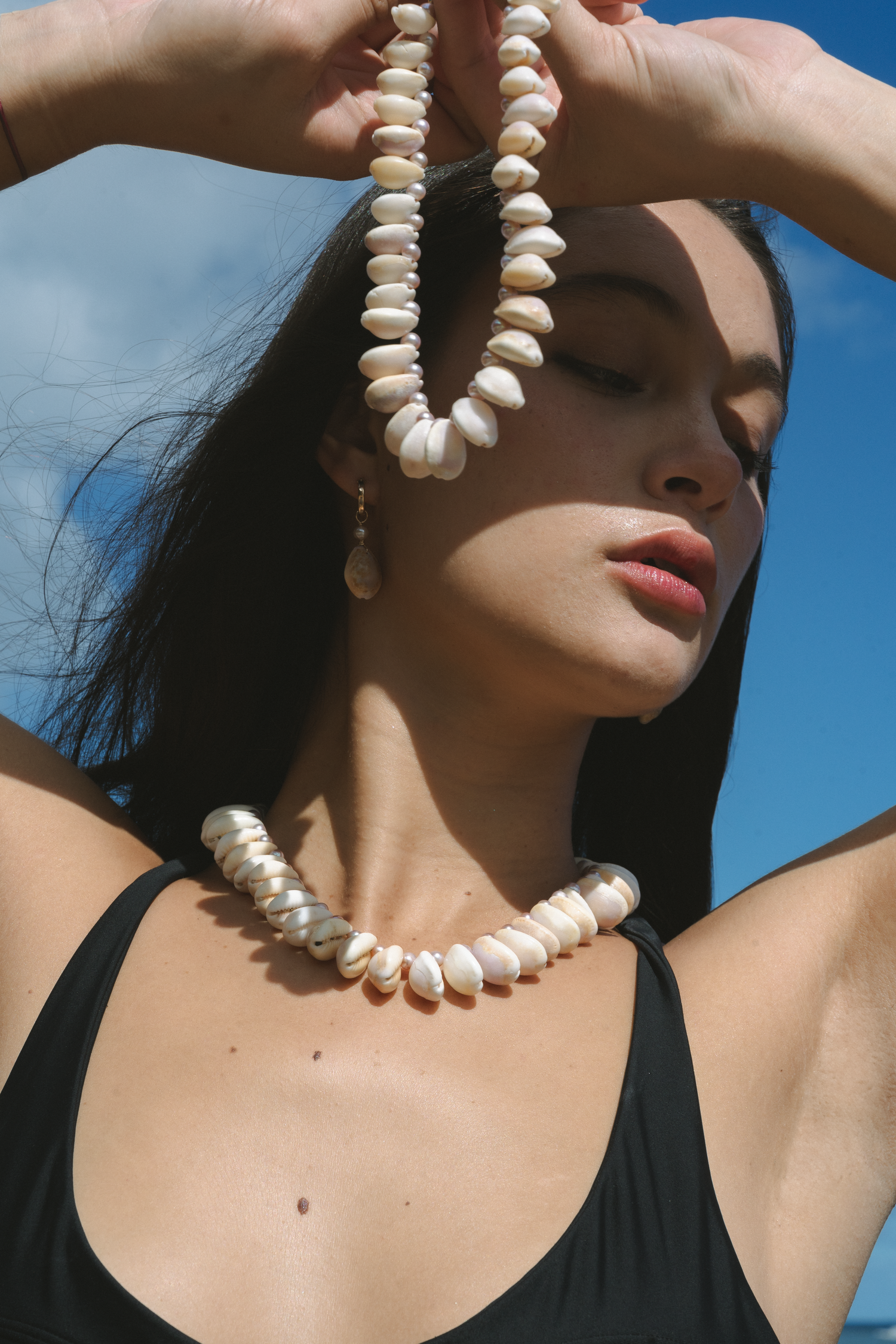 Close-up fashion shot featuring a necklace against a blue sky backdrop.