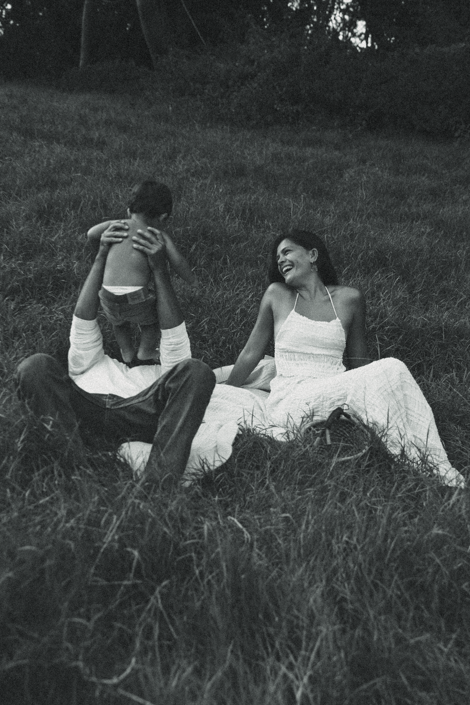 Black and white photo series showing figures in white clothing lying in tall grass at different angles.