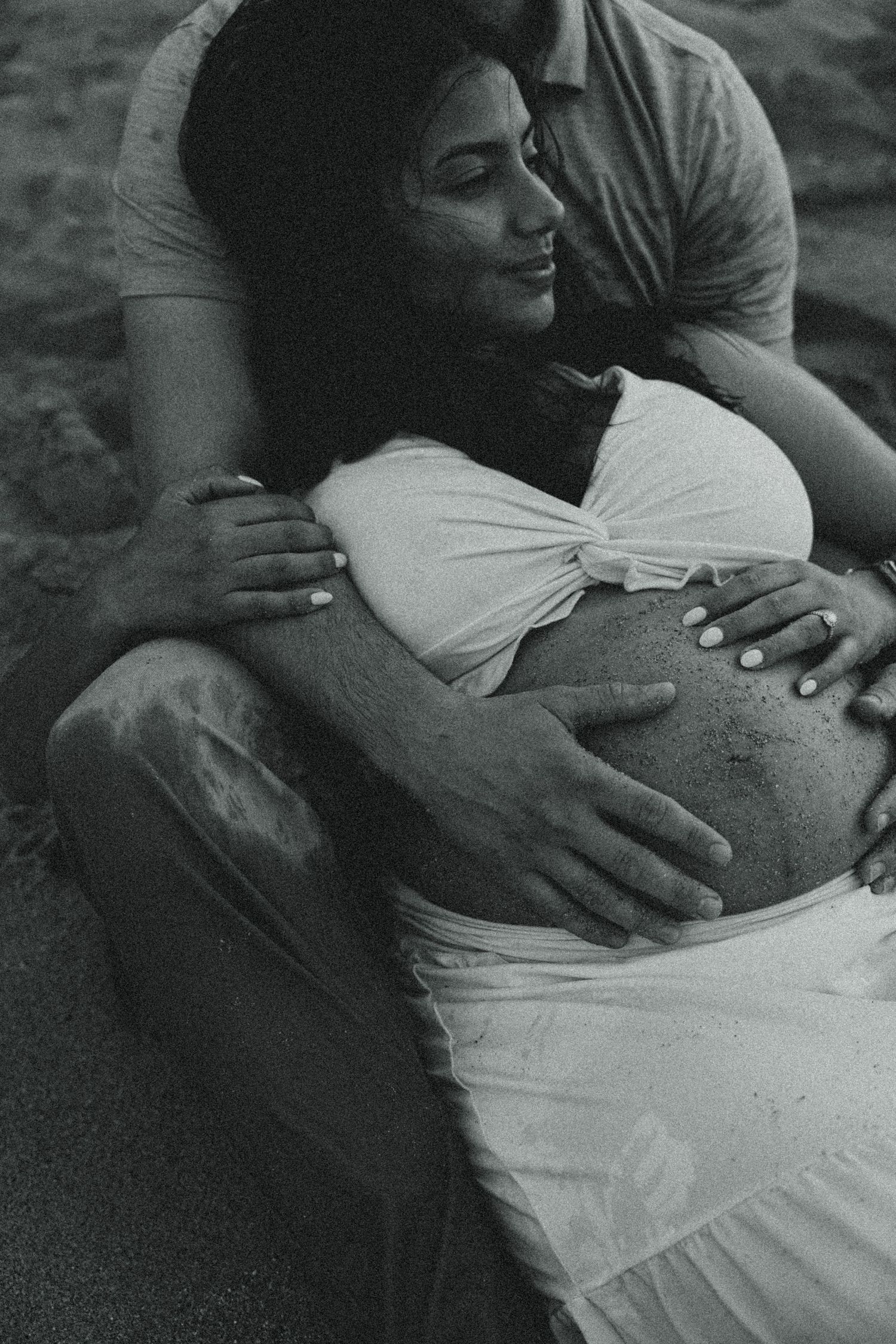 A series of black and white close-up photos showing hands gently resting on a pregnant belly.