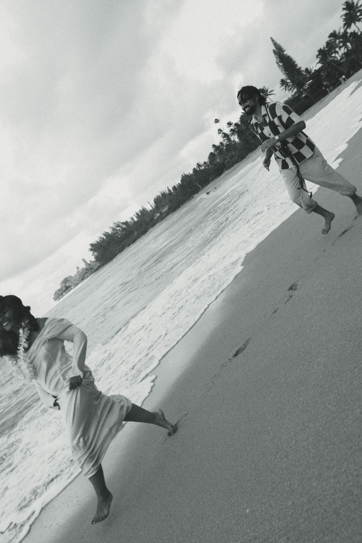 Black and white sequence of a person cartwheeling on a sandy beach with ocean waves and palm trees in the background.