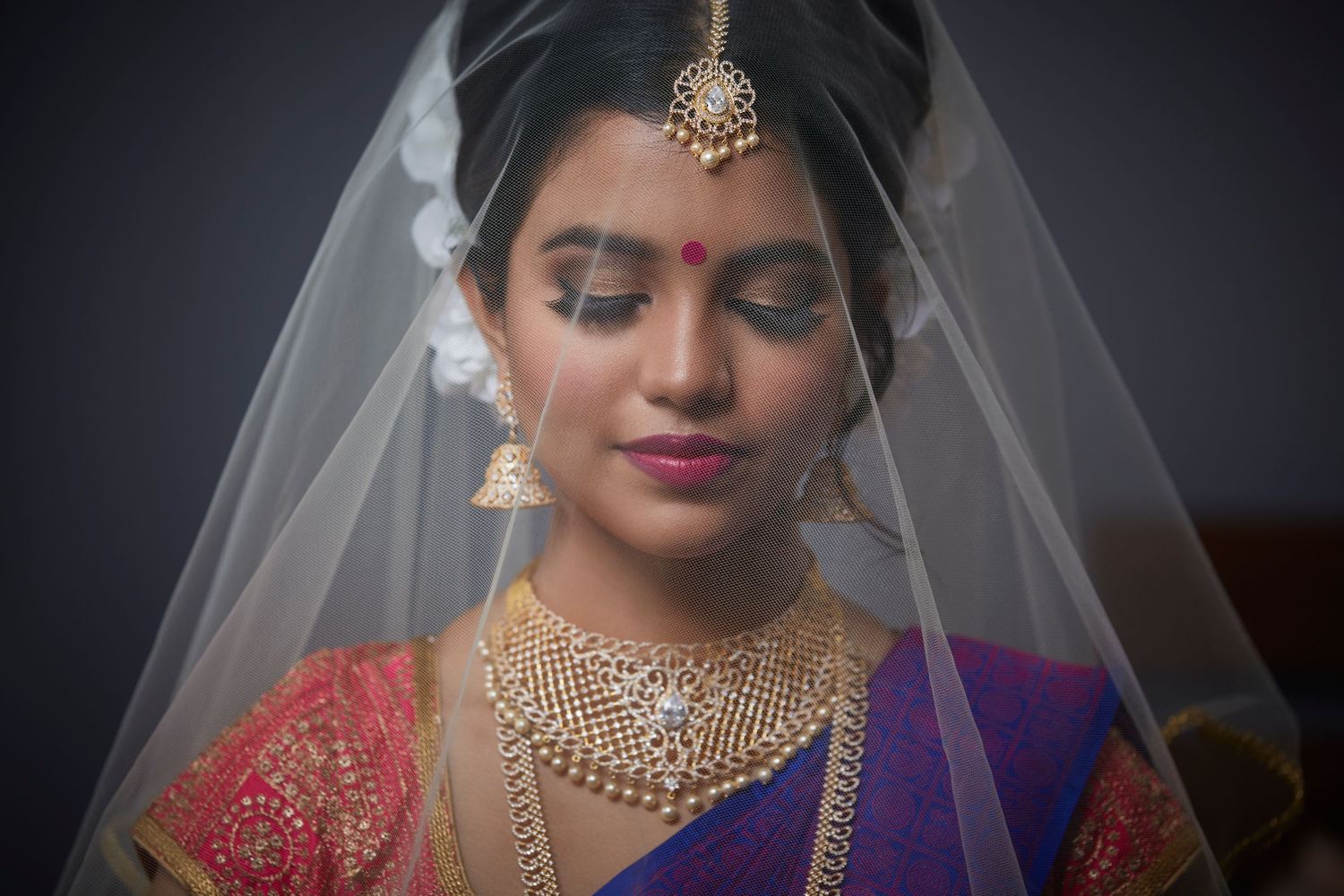 Close-up details of bridal jewelry and makeup in dramatic lighting.