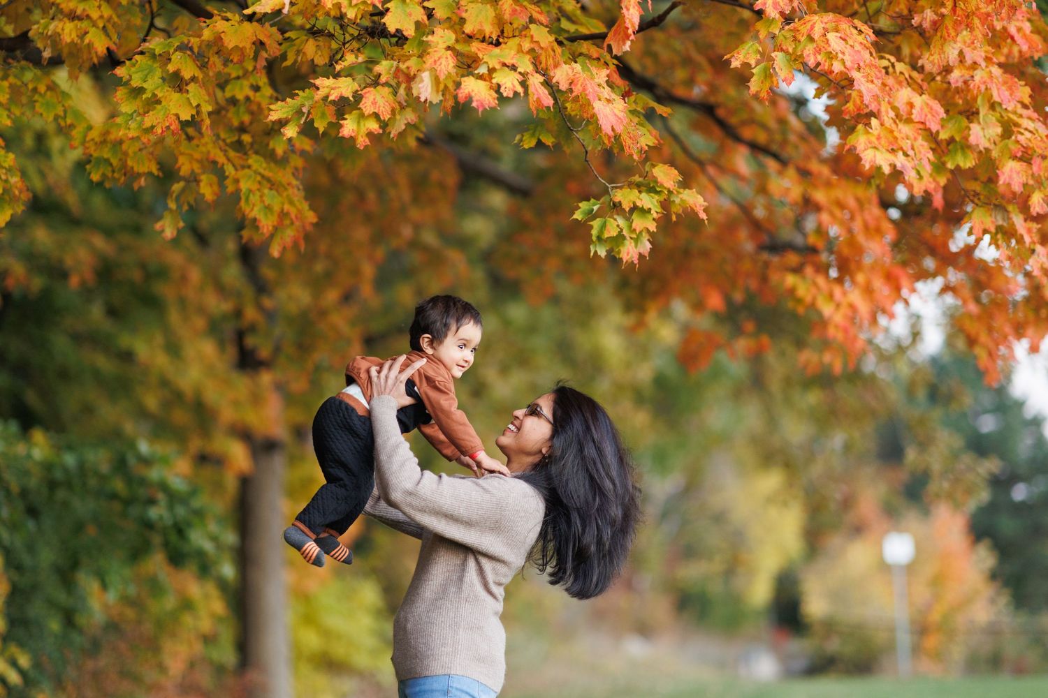 A couple embraces under vibrant autumn trees with golden leaves during a romantic outdoor photoshoot.