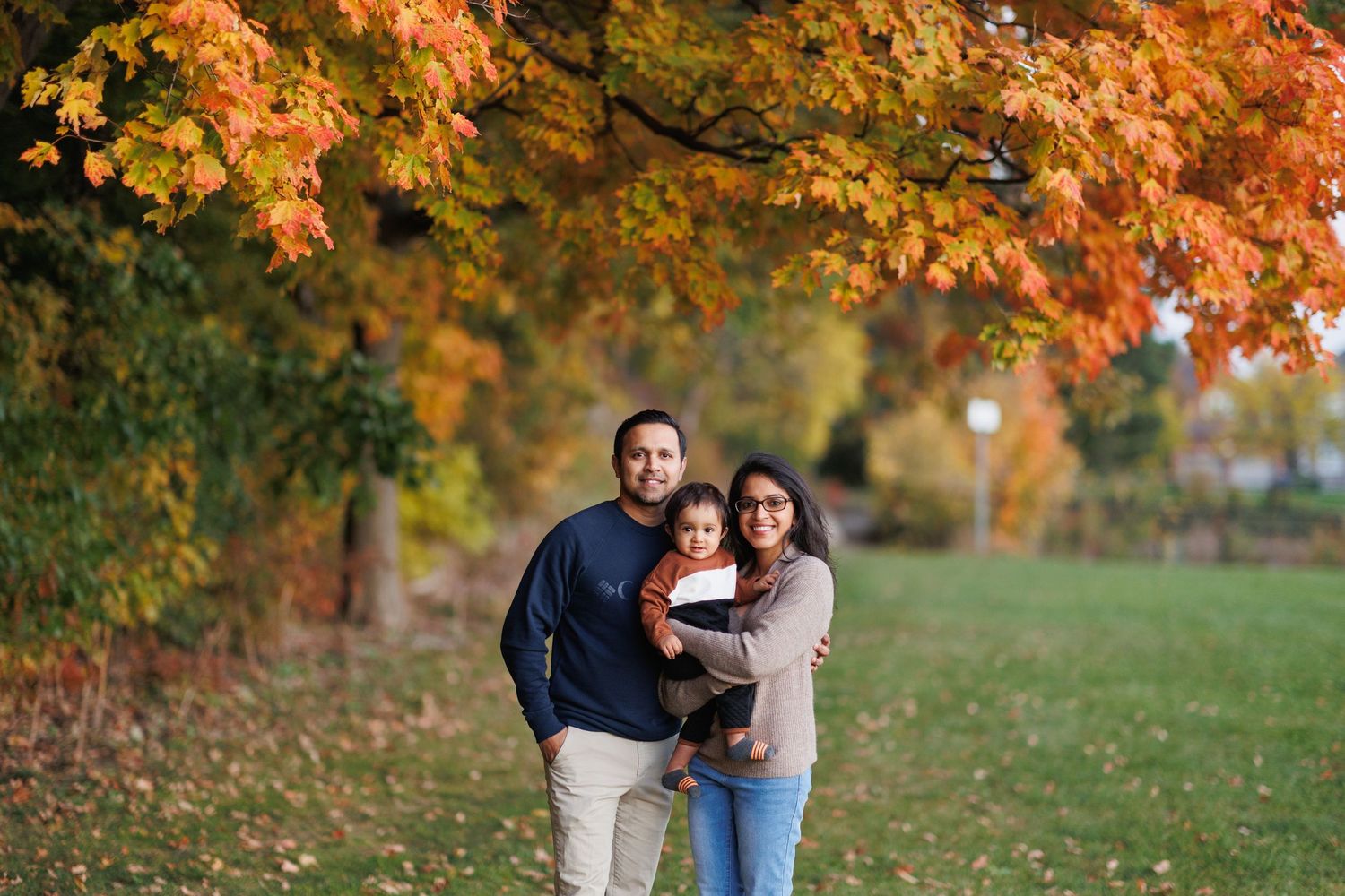 A couple enjoys a romantic autumn day together in a park surrounded by vibrant orange and yellow fall foliage.