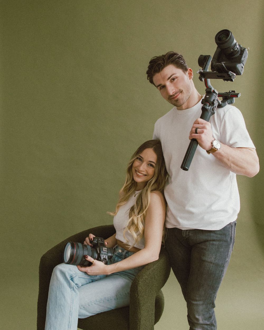 Photographers with professional camera equipment posing in studio against green background.