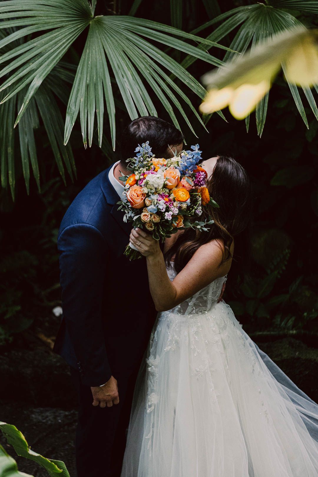 Romantic kiss covered by floral bouquet of bride and groom during portraits, captured by Cleveland wedding photographer.