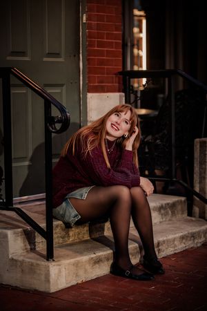 A moody photoshoot on brick steps featuring burgundy clothing and dramatic lighting.