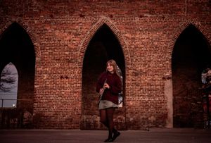 A series of five photos showing a person in black clothing posing against a rustic brick wall with arched openings.