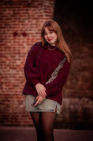 A person in a burgundy sweater poses against a brick wall background in a series of casual portrait shots.