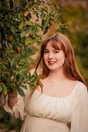 A portrait session in a citrus grove featuring a white peasant dress and natural autumn lighting.