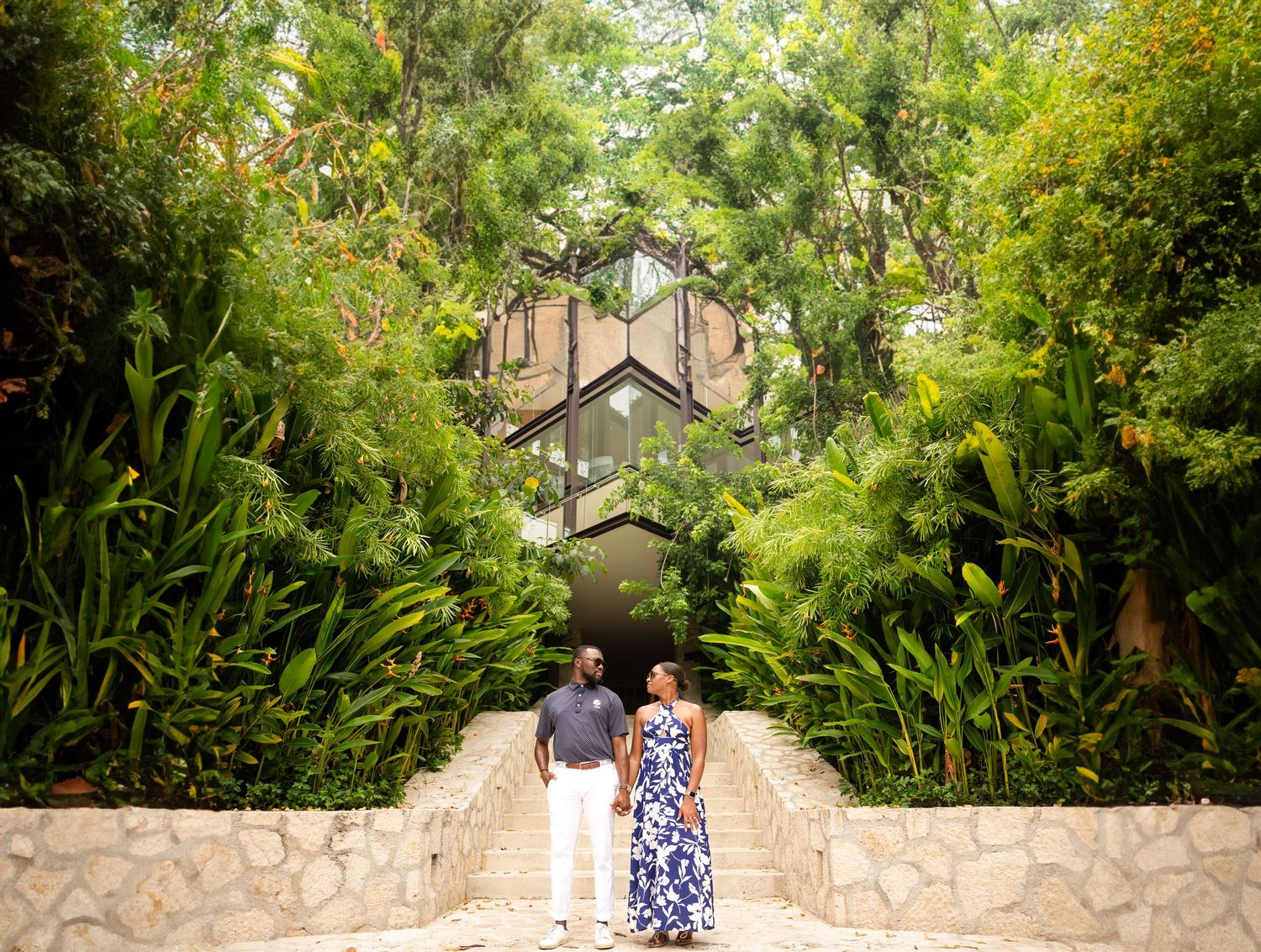Scenic garden pathway leading to architecture through lush tropical foliage.