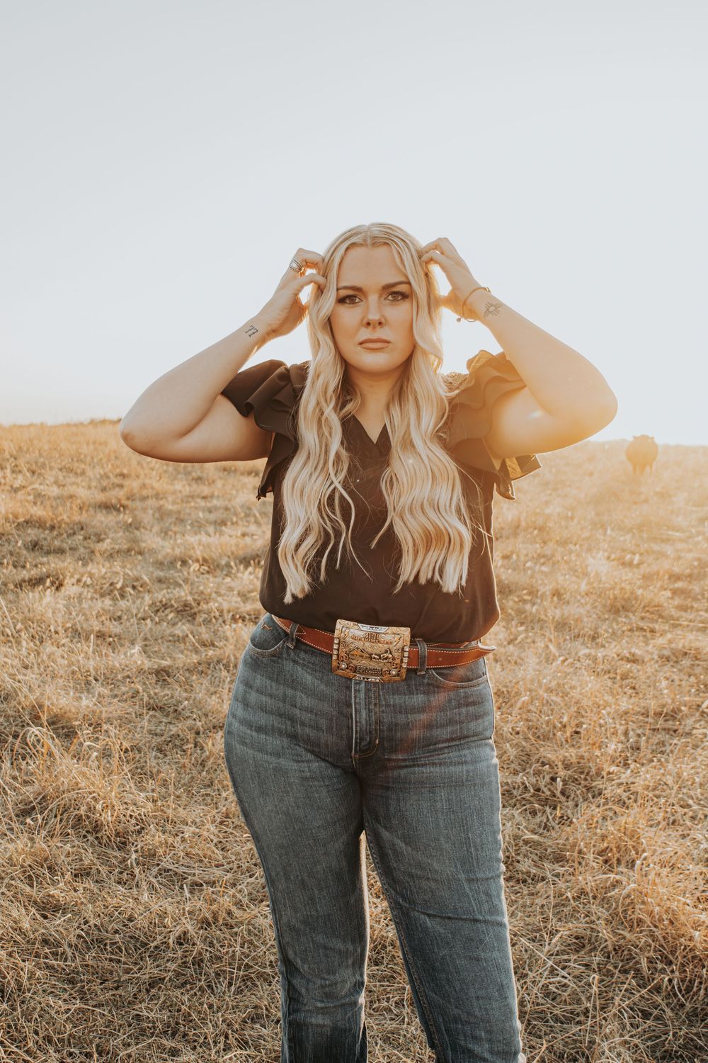Sun-drenched portrait in western wear against golden field background.