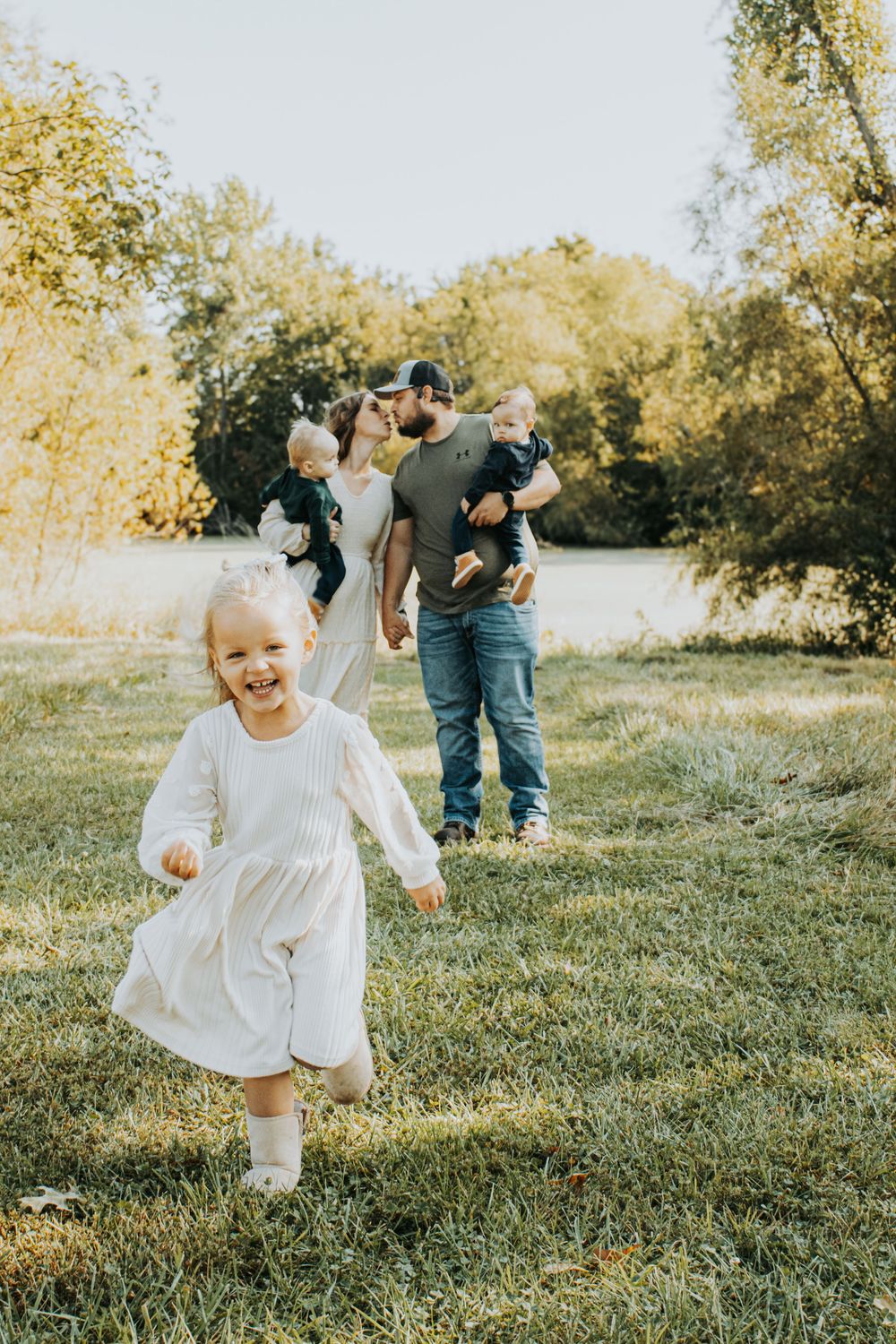 A joyful scene on a sunny autumn day as a group gathers outdoors on grassy lawn surrounded by golden trees.