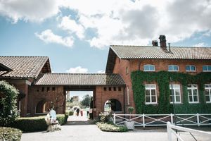 Rustic red brick wedding venue courtyard with ivy-covered walls under a sunny blue sky.