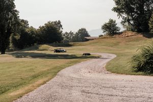 Winding gravel path through scenic green golf course landscape with trees on a hazy day.