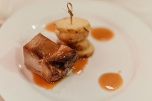 Elegant plated pork dish with caramelized onion and rich sauce served at a wedding reception.