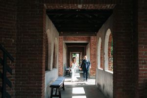 Bride and groom share a romantic moment in a sunlit brick archway corridor at their wedding venue.