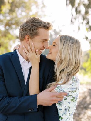 A romantic couple shares an intimate moment outdoors with soft natural lighting and dreamy bokeh effect in the background.
