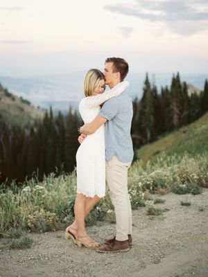 Husband and wife tenderly hug and kiss gorgeous pine tree canyon background