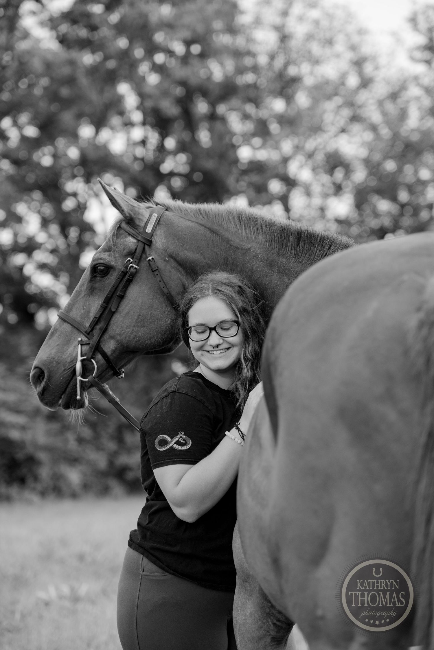 A black and white portrait of a horse and its handler in an outdoor setting.