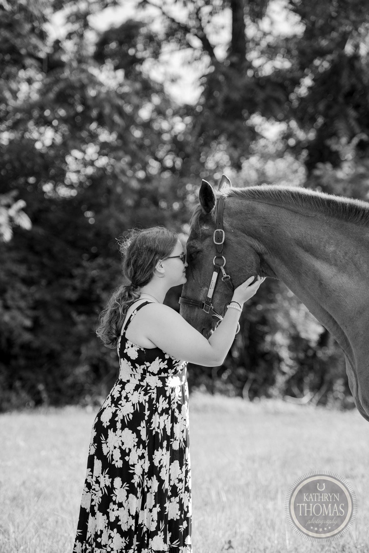 A tender moment between a horse and handler against a blurred forest background.