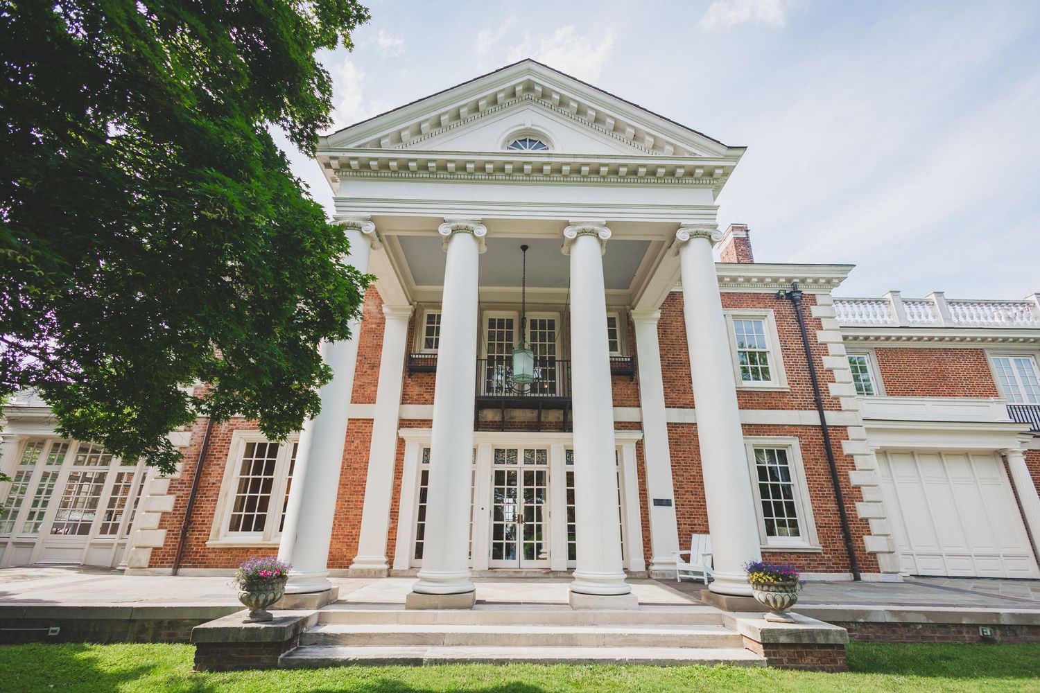 Elegant white colonial mansion with grand columns and triangular pediment showcases classic American architecture.
